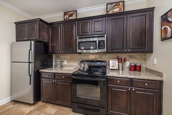 Chef's kitchen with stainless steel appliances, including built-in microwave oven and espresso wood cabinetry